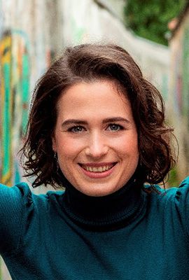 Das Portrait zeigt Robin Ziehbrunner mit schulterlangen, welligen, braunen Haaren und einem freundlichen Lächeln.